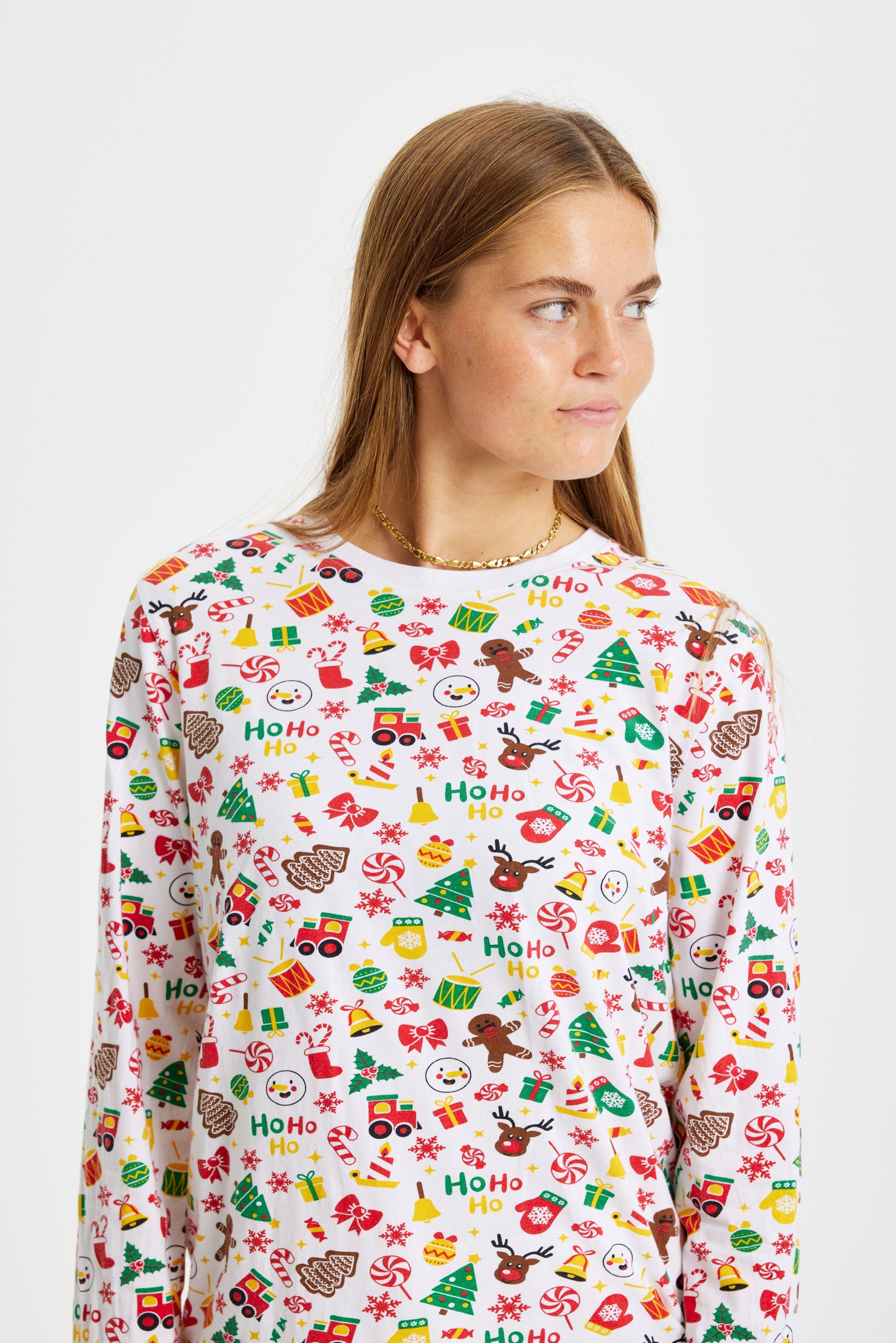 Une femme regardant de côté portant un pyjama de Noël blanc.